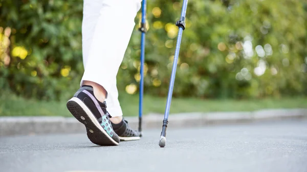 Vrouw in zwarte schoenen lopen met stokken bijhouden — Stockfoto