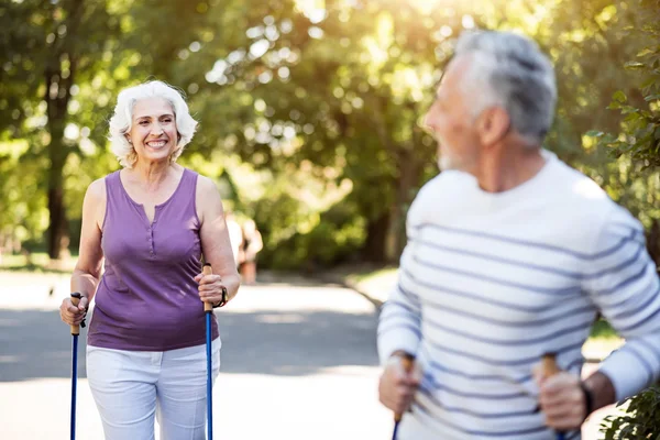 Smiley graue Frau schaut Ehemann beim Sport im Park an — Stockfoto