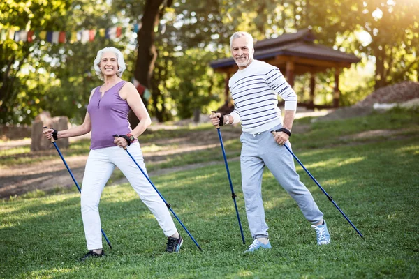 Two elderly people performing exercises with tracking sticks — Stock Photo, Image