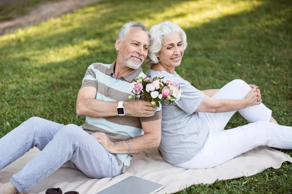 Šťastný let manželský pár sedí na trávě v parku — Stock fotografie