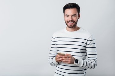 Mutlu sakallı adam gülümseyen ve cep telefonu kullanarak.