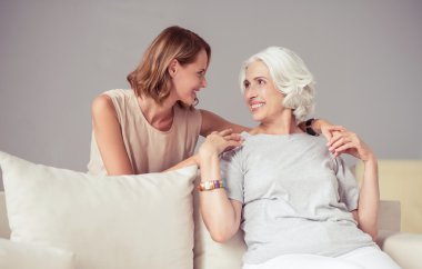 Cheerful delighted mother and her adult daughter resting at home