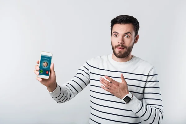 Homem barbudo surpreso demonstrando celular . — Fotografia de Stock