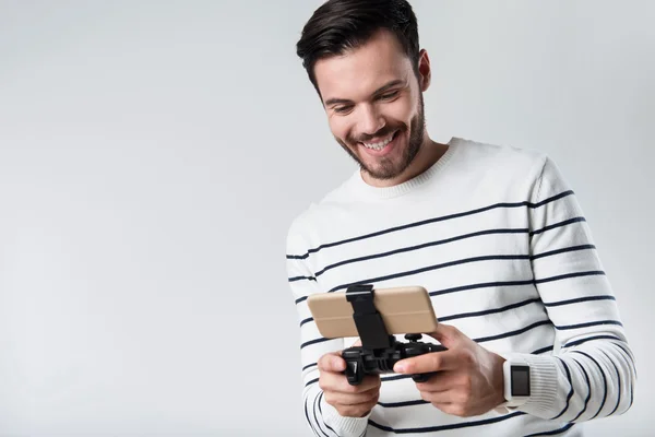 Homem barbudo alegre sorrindo e usando gamepad portátil . — Fotografia de Stock