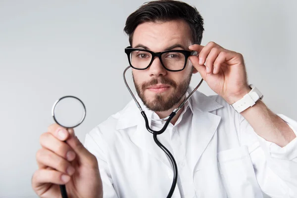 Homme barbu concentré tenant un stéthoscope . — Photo