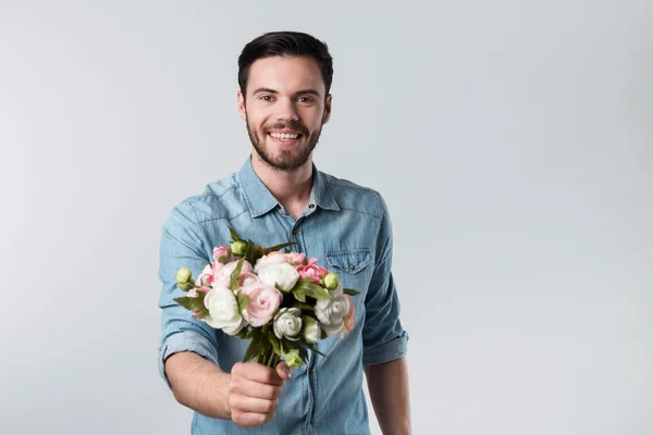 Lycklig stilig ung man som håller ett gäng blommor. — Stockfoto