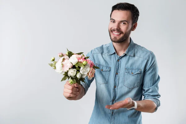 Homem barbudo romântico sorrindo e segurando um monte de flores . — Fotografia de Stock