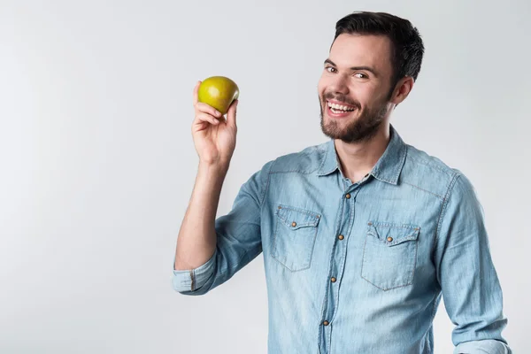 Happy bearded man smiling and holding an apple. — Stock Photo, Image