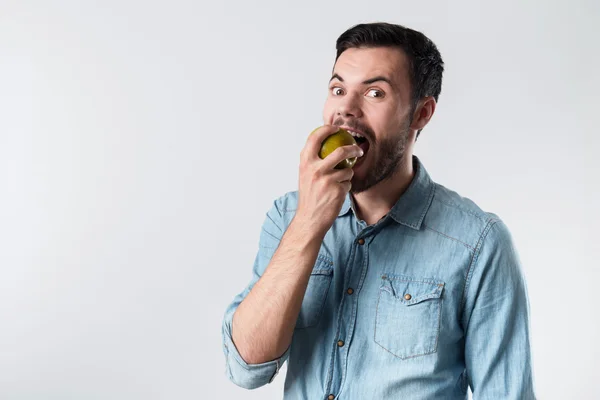 Hombre barbudo energizado sonriendo y sosteniendo una manzana . —  Fotos de Stock