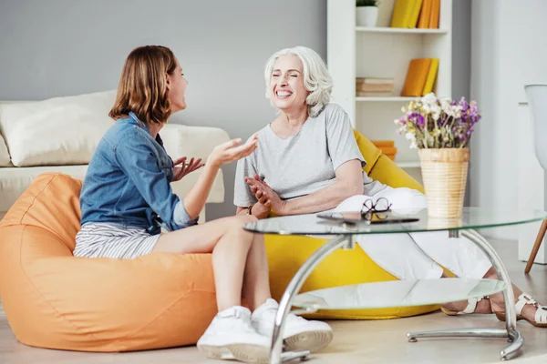 Mulher sorridente alegre e sua mãe tendo uma conversa animada — Fotografia de Stock