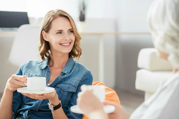 Радостная женщина пьет кофе со своей матерью — стоковое фото