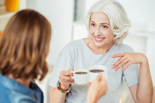 Positive aged woman drinking tea with her adult daughter — Stock Photo, Image