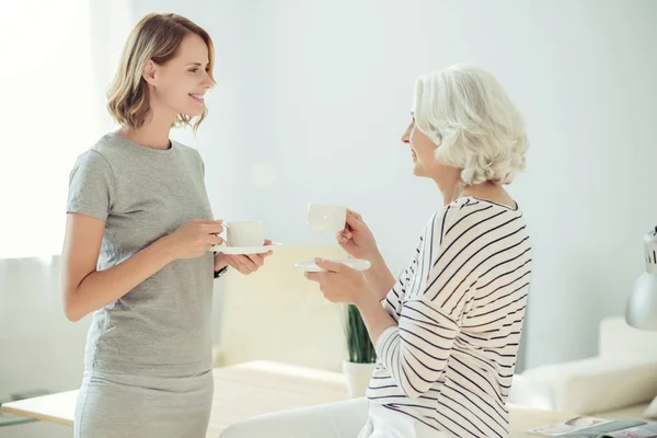 Vrolijke vrouw en haar senior moeder drinken koffie — Stockfoto