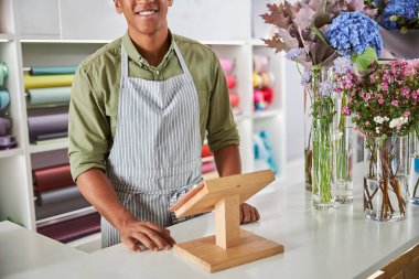 Neşeli genç adam çiçekçide eğleniyor.