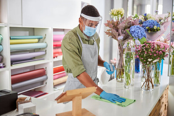 Shop assistant doing desinfection in flower shop