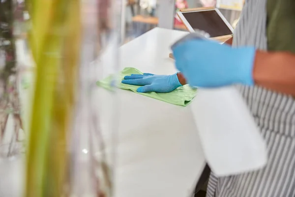 Prodejna asistent čištění povrchů s dezinfekcí na květinářství — Stock fotografie