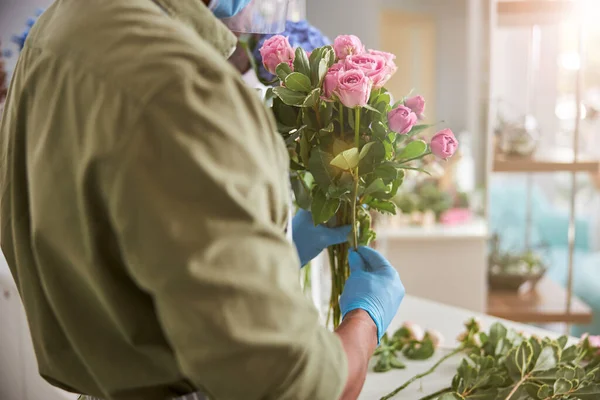 Asistente de tienda sosteniendo racimo de rosas rosadas — Foto de Stock