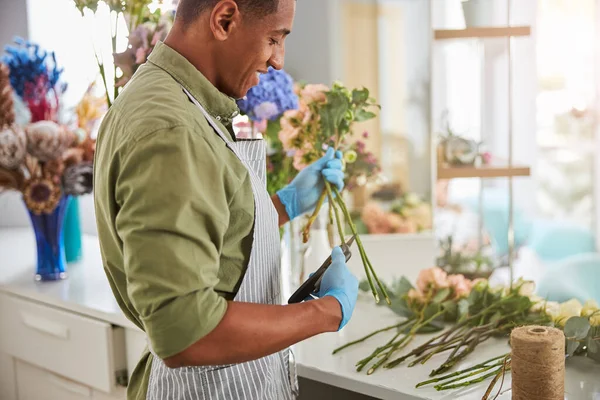 Joven alegre haciendo ramo de rosas en el trabajo — Foto de Stock