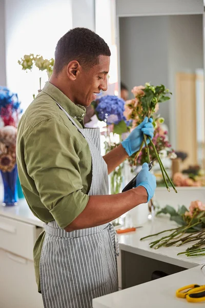 Feliz florista joven haciendo ramo fresco de rosas —  Fotos de Stock