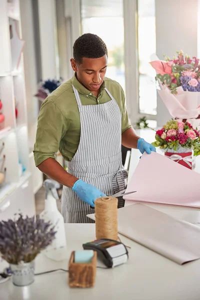 Jonge bloemist wikkeling boeket in moderne winkel — Stockfoto