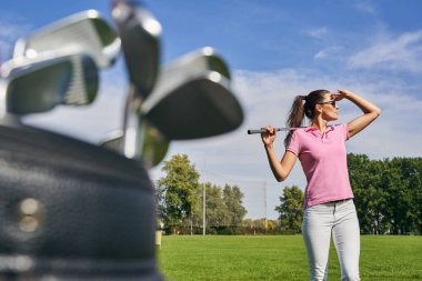 Omzunda golf sopası olan bir kadın.