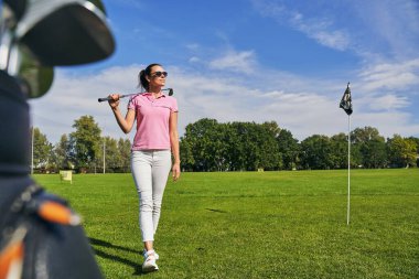 Yeşil çimenlerde yürüyen kadın golfçü