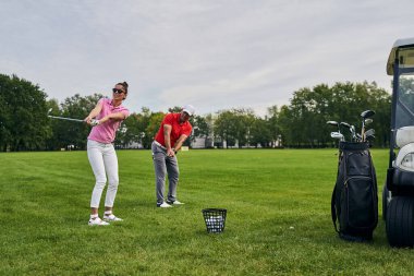 Yeni golfçü ve koçu birlikte antrenman yapıyor.