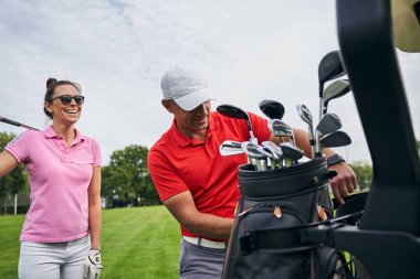 Golf hocasının arkasında duran enerjik, sportif bayan.