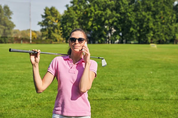 Smiling perempuan dengan klub golf panggilan pada ponsel nya — Stok Foto