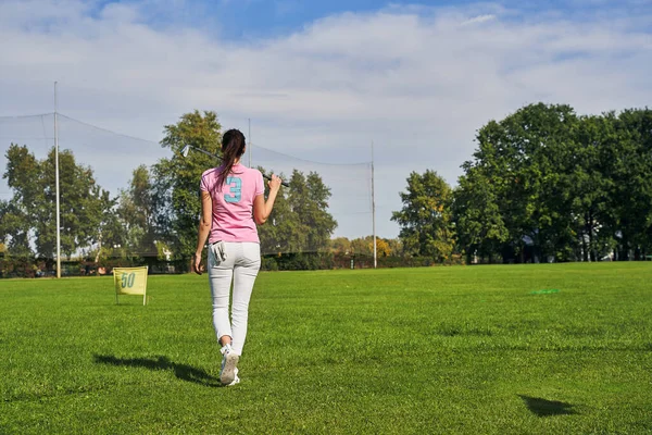 Молода жінка-гравець, що йде через поле для гольфу — стокове фото