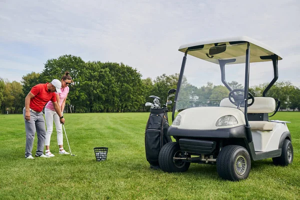 Mulher golpeando a bola de golfe com um putter — Fotografia de Stock