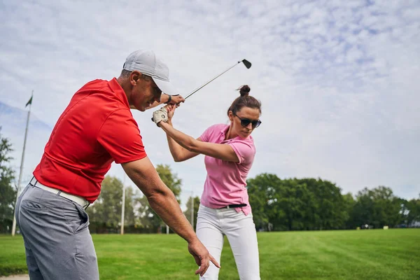 Professor experiente instruindo uma jogadora de golfe — Fotografia de Stock