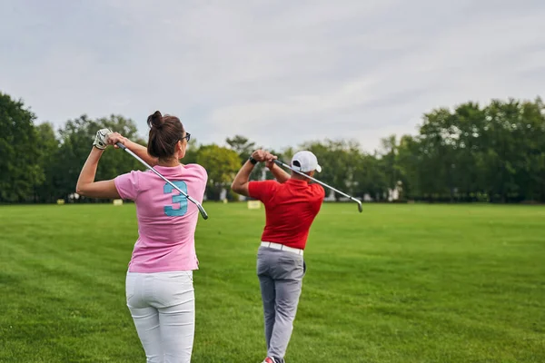 Dwóch sportowców trenujących huśtawki golfowe na torze jazdy — Zdjęcie stockowe