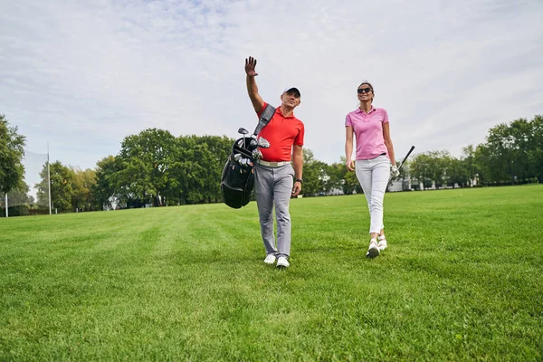 Golfista feminina e seu personal trainer olhando para a distância — Fotografia de Stock