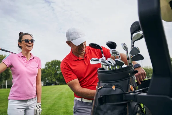 Senhora desportiva de alto espírito que está atrás de seu instrutor de golfe — Fotografia de Stock