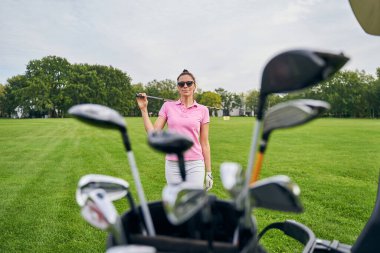 Beyaz kadın golfçü çimlerin üzerinde duruyor.