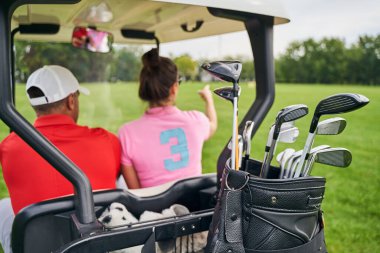 Şoför ve bir yolcu golf arabasında oturuyor.