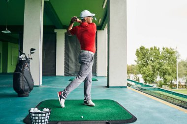 Ciddi erkek atlet golf vuruşlarını çalışıyor.