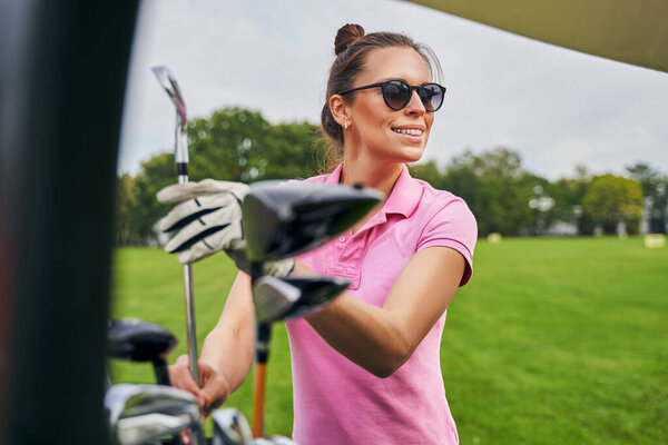Smiling happy golfer in sunglasses gazing away