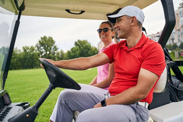 Sorrindo homem dando uma carona para uma senhora golfista — Fotografia de Stock