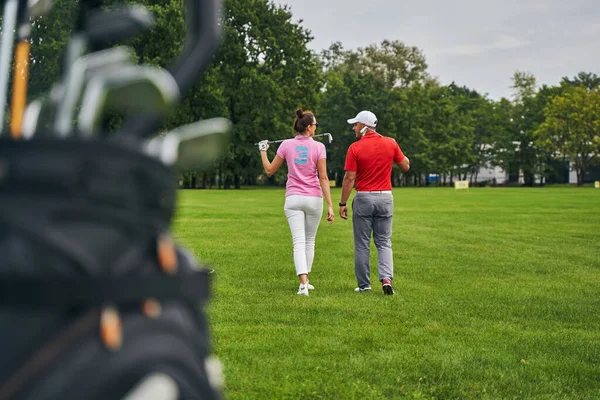 Duas pessoas com tacos de golfe sorrindo um para o outro — Fotografia de Stock