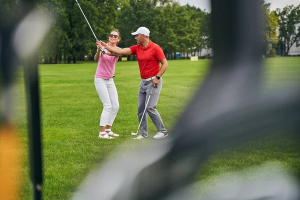 Sorrindo iniciante do sexo feminino tendo uma lição de golfe de um profissional — Fotografia de Stock