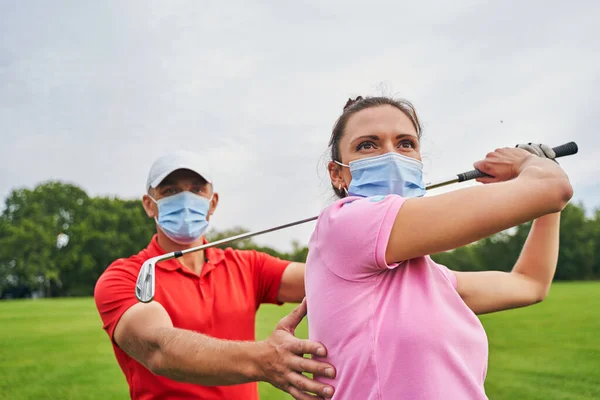 Sportlerin mit Golfschläger über dem Kopf schaut weg — Stockfoto
