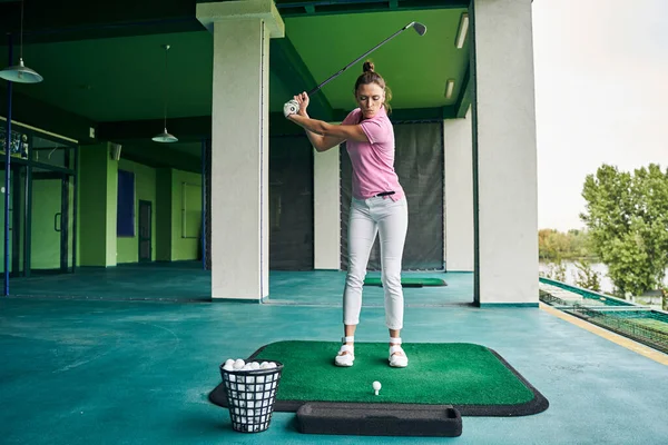 Concentrated sportswoman teeing off with a driver — Stock Photo, Image