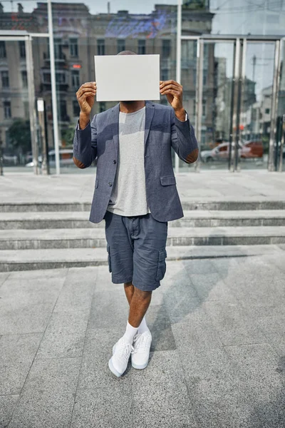 Giovane uomo internazionale che si copre il viso con la carta — Foto Stock