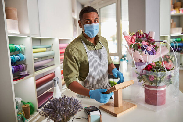 Flower shop worker making calculations on an electronic tablet