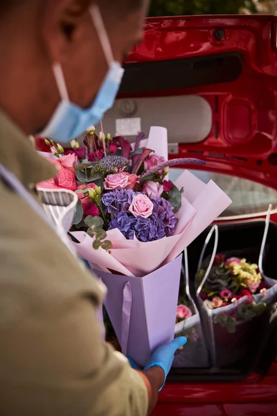 Bloemenspecialist laadt een posy in een kofferbak — Stockfoto