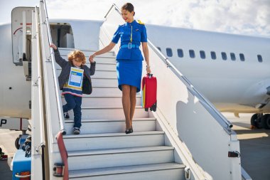 Yardımsever hostes bir çocuğun uçaktan inmesine yardım ediyor.