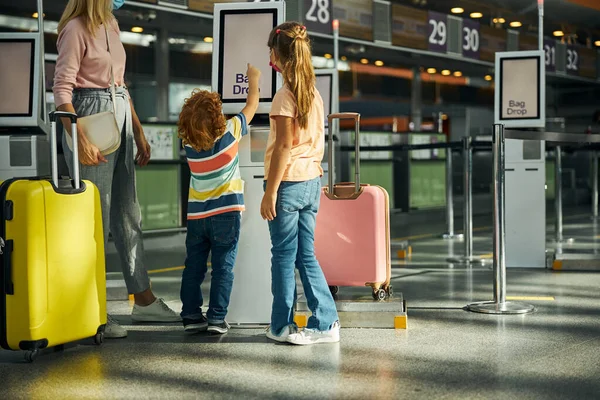 Curious boy touching a screen of a bag drop kiosk