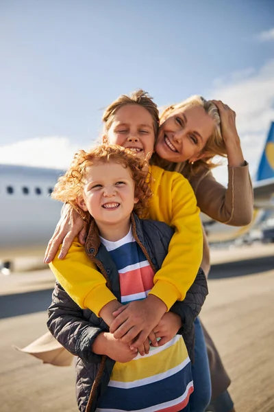 Усміхнені брати і сестри з матір'ю близько до літака — стокове фото